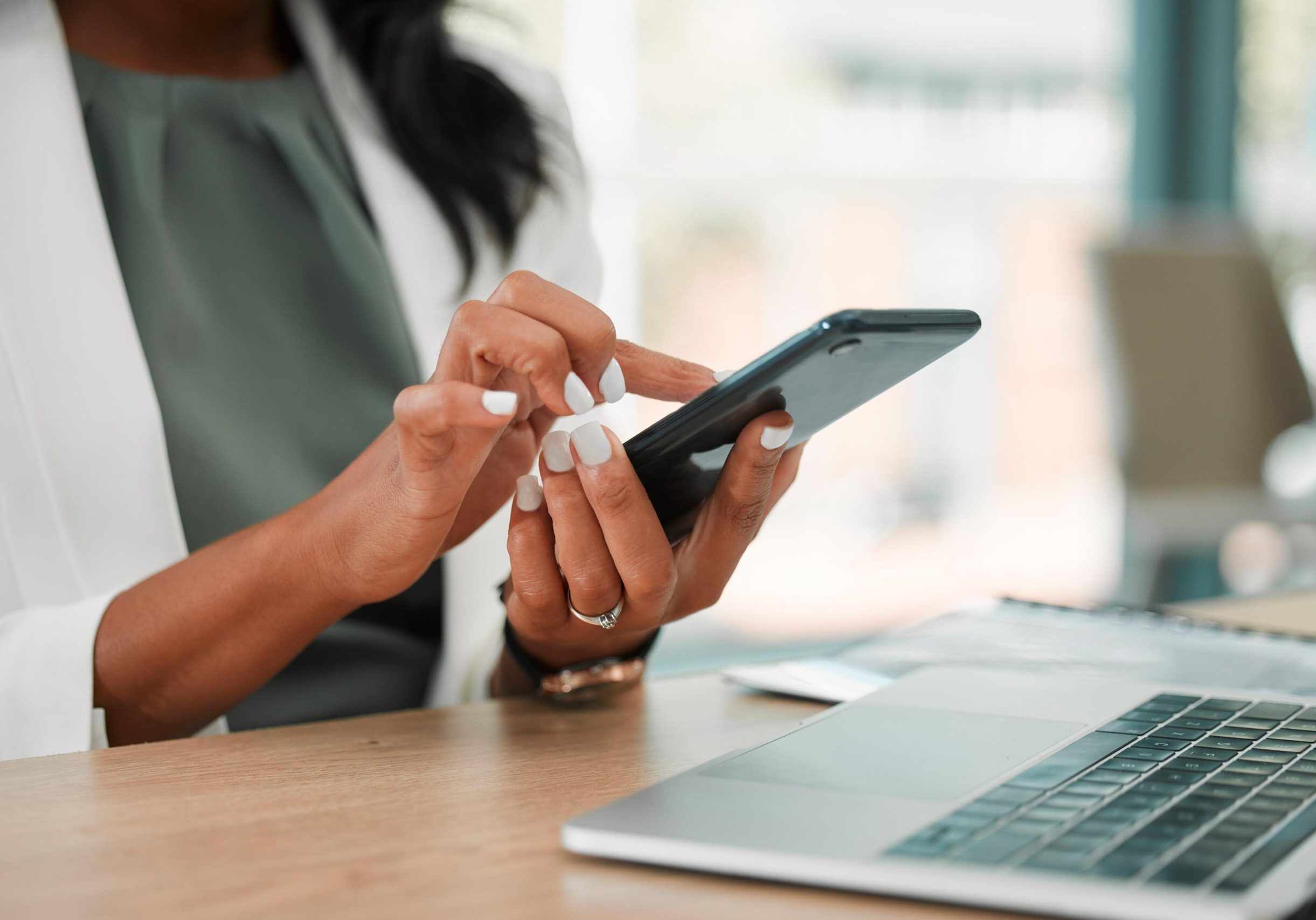 Person using smartphone at office desk.